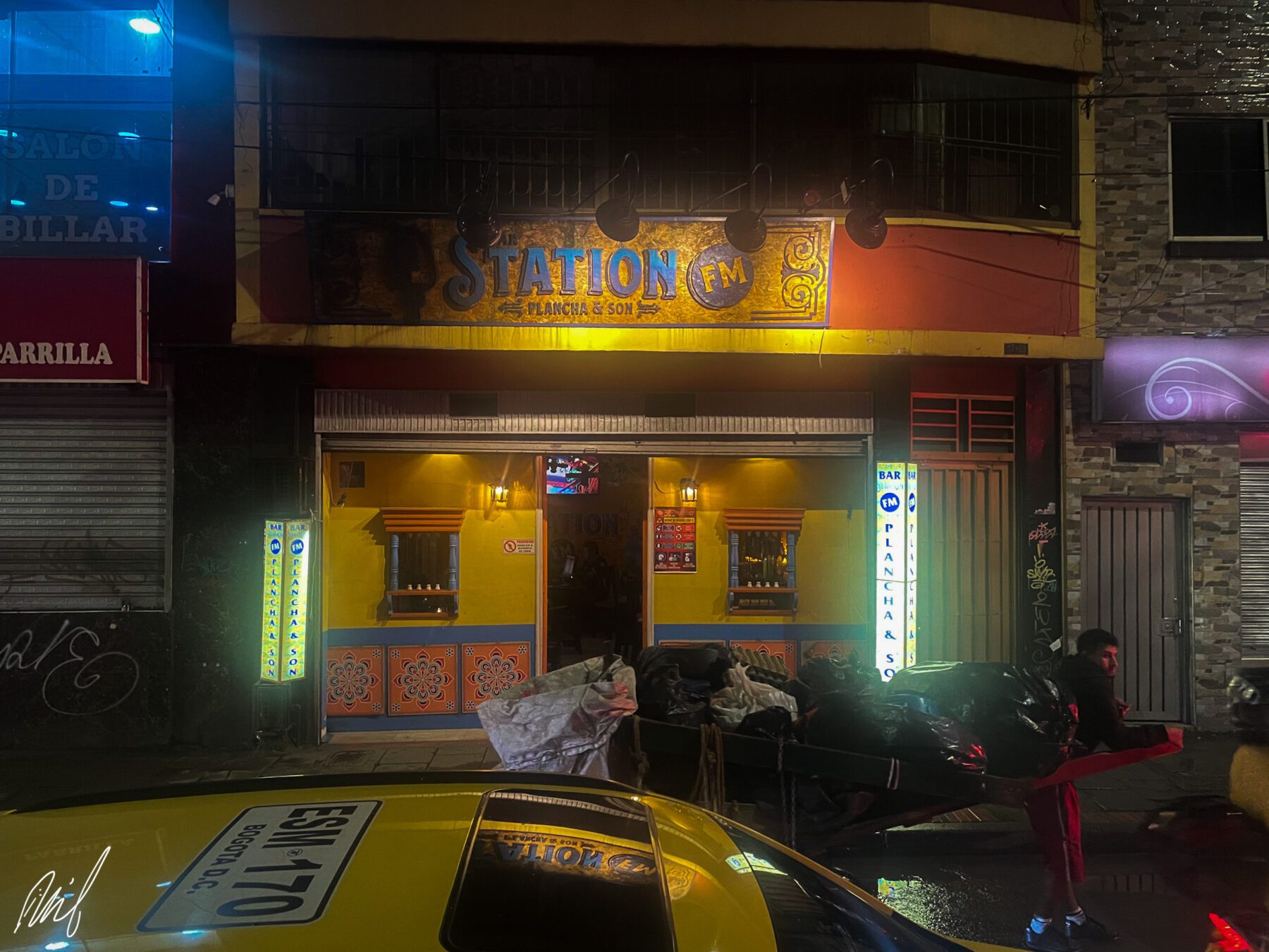 A taxi parked in front of a restaurant at night.