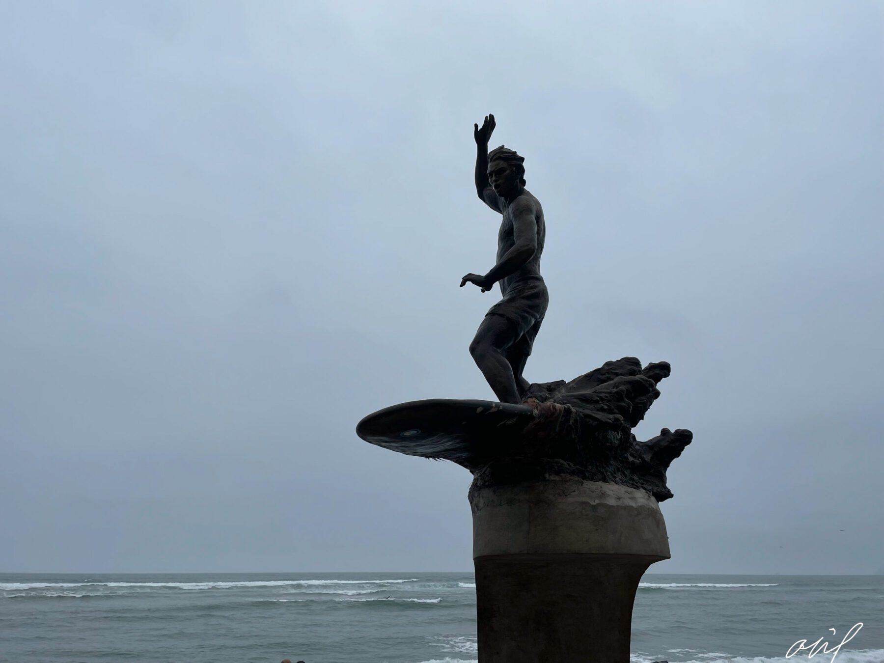 A statue of a surfer standing on top of a Peru surfboard.