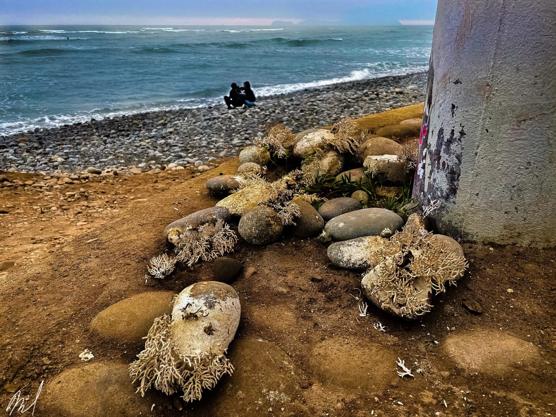 A pile of Peru on the beach next to a pole.