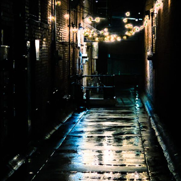 An alleyway lit up at night with Montana string lights.